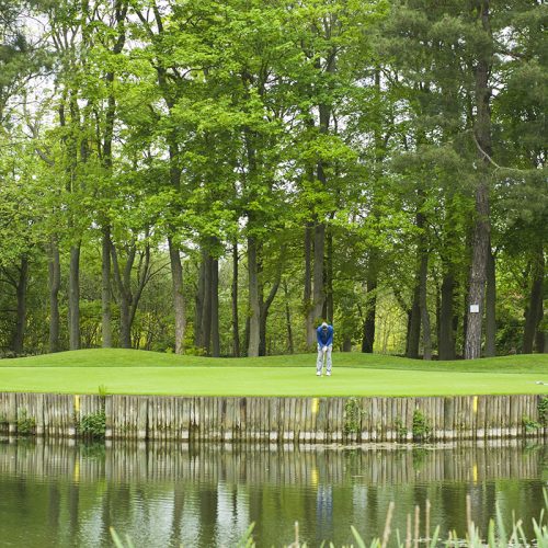 Image of a man playing golf by a lake